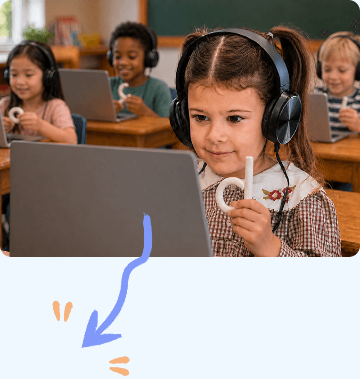 Children at their desks holding clay letters they shaped while working on laptops